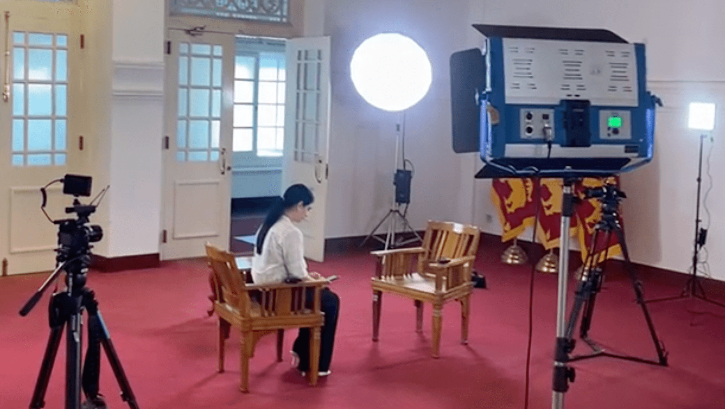 A film interview setup with cameras, lights and chairs arranged in a large room